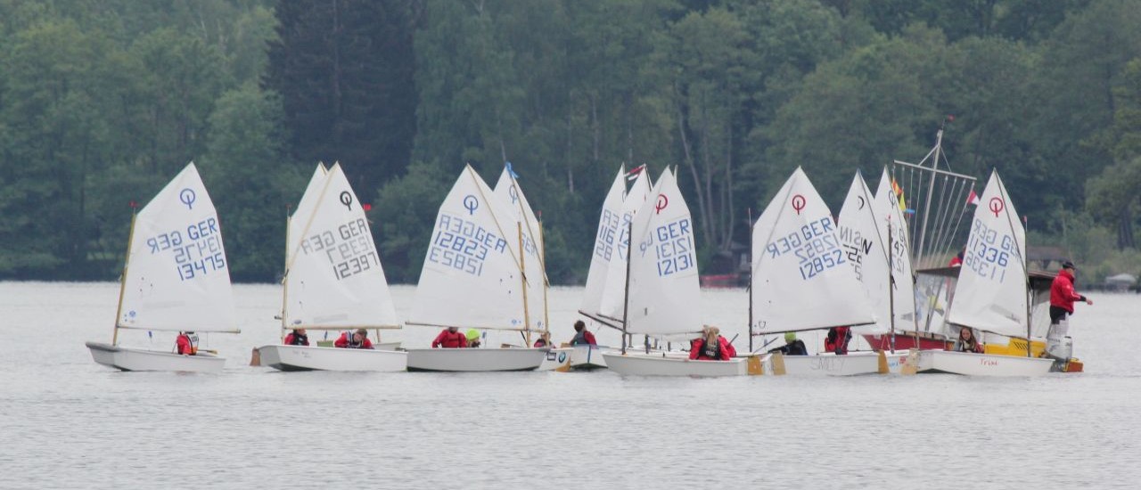 Startverschiebung? Mittagessen? Die Optis schaaren sich um das Startboot. 